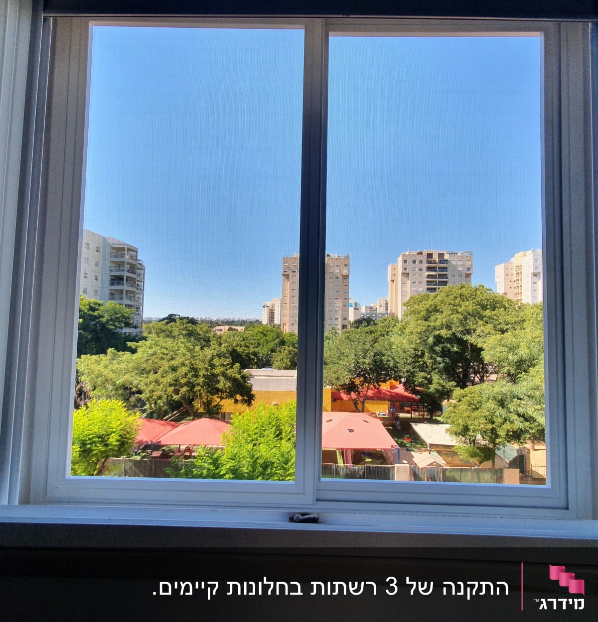 חלון אלומיניום עם נוף עירוני ועצים ברקע